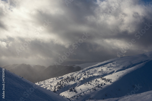 Freeride ski trail on a mountain slope. The mountain range is covered with snow on a background of bright cloudy sky. Winter mountain landscape.