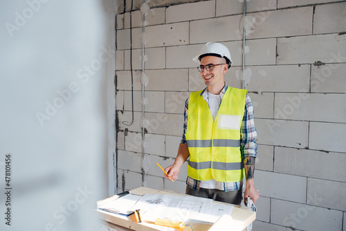 Socialy engaged construction engineer drawing on a blueprint on atable photo