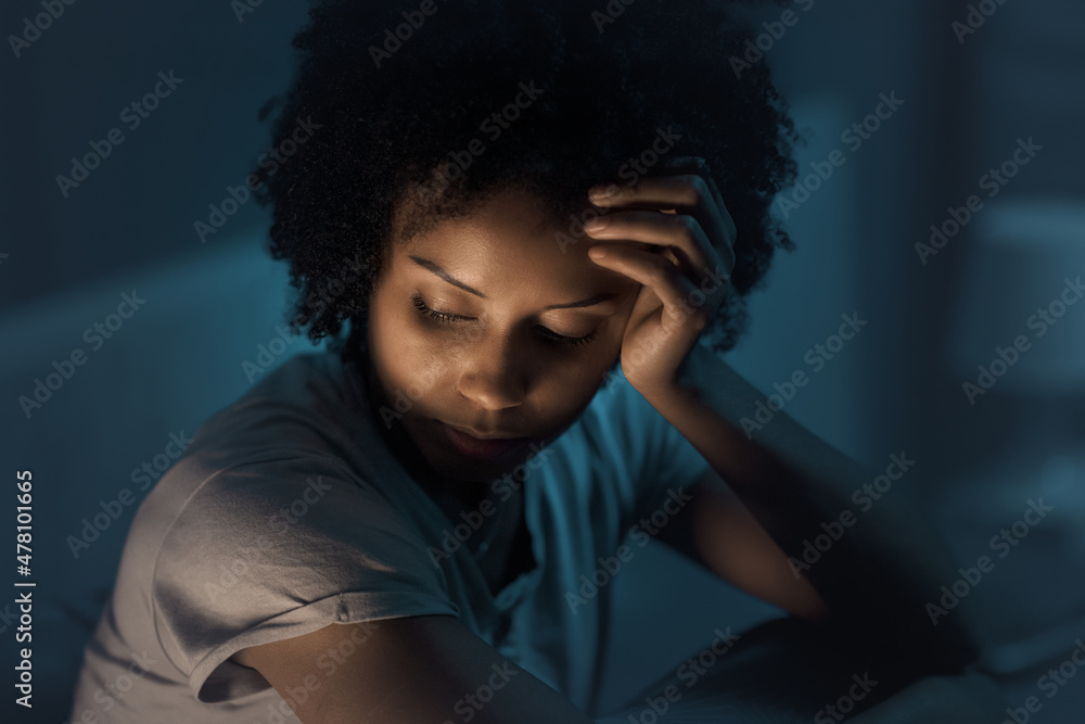 Sleepless african american woman sitting in bed at night