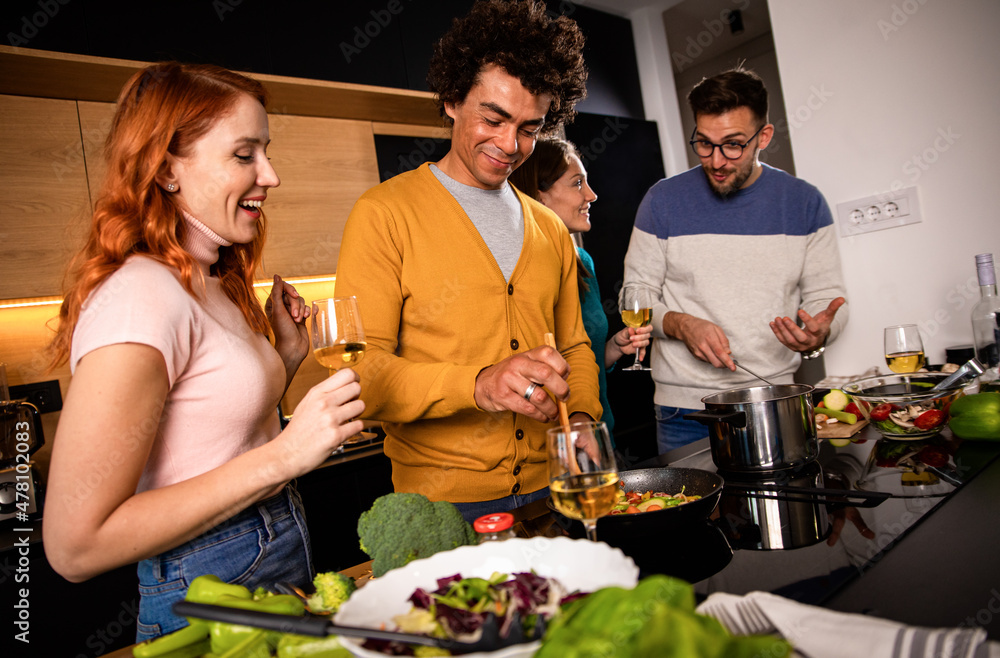 Group of friends preparing vegetarian meal in a kitchen at home. Group of friends preparing vegetarian meal in a kitchen at home.