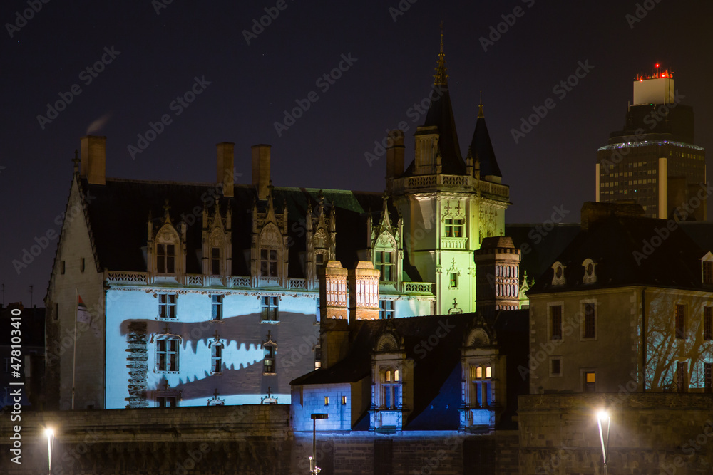Château médiéval et tour moderne de nuit, éclairage coloré et crocodile en ombre chinoise sur façade
