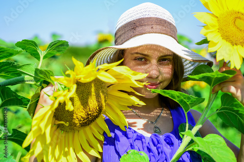 Good-looking gardener. concept of summer vacation. rich harvest and agriculture. happy childhood. kid wear straw summer hat. child in field of yellow flowers. teen girl in sunflower field