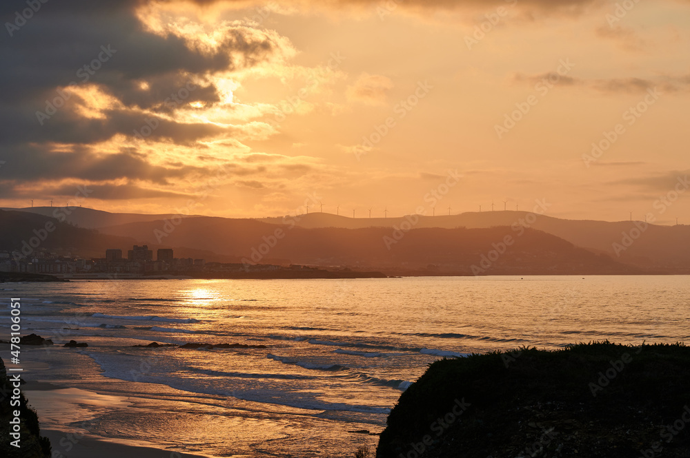 Breathtaking scenery of calm sea and beach under bright orange sundown sky with clouds in evening Breathtaking scenery of calm sea and beach under bright orange sundown sky with clouds in evening