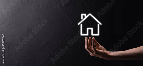 Male hand holding house icon on blue background. Property insurance and security concept.Real estate concept.Banner with copy space.