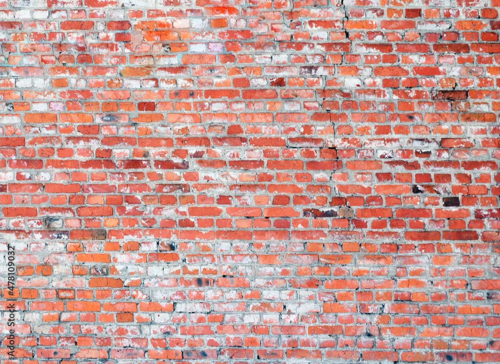 Naklejka premium The wall is made of red bricks covered with cement and old paint. Peeling paint.