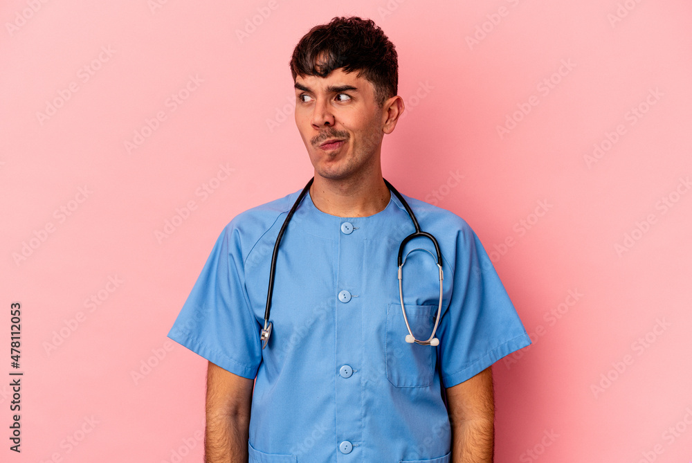 Young mixed race nurse man isolated on pink background confused, feels doubtful and unsure. Young mixed race nurse man isolated on pink background confused, feels doubtful and unsure.