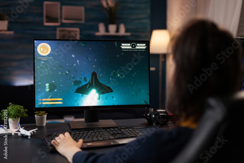 Gamer using keyboard to play digital video games. Woman playing online game with control console on computer, doing fun activity. Player using modern gaming equipment in cyberspace. photo