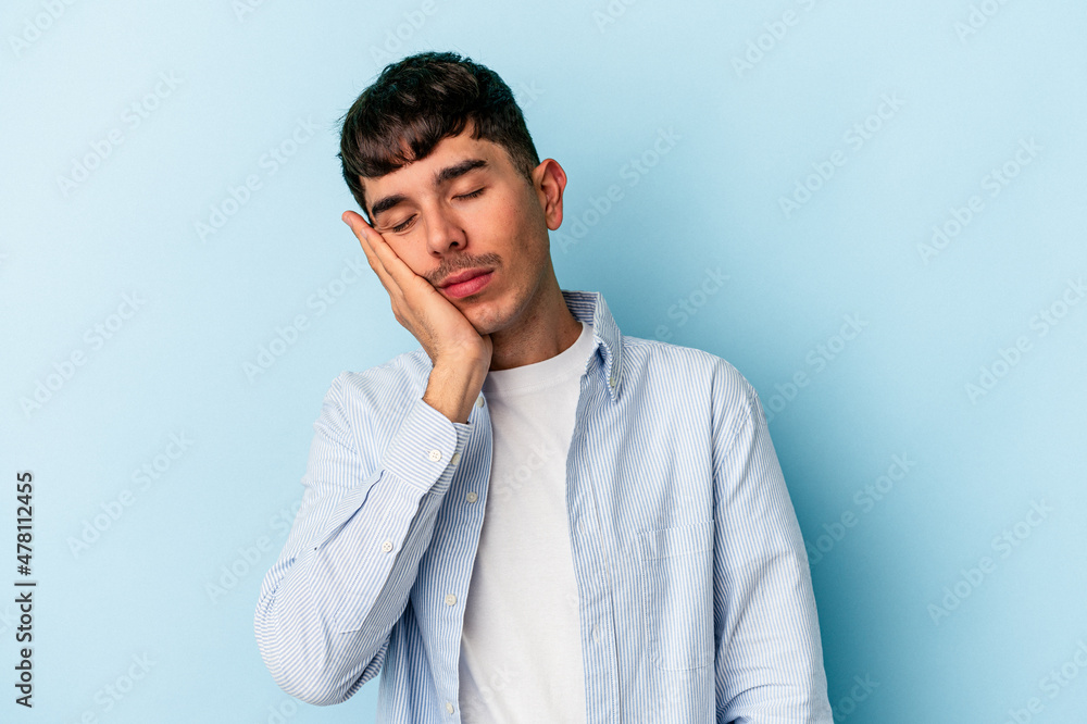 Young mixed race man isolated on blue background who is bored, fatigued and need a relax day. Young mixed race man isolated on blue background who is bored, fatigued and need a relax day.