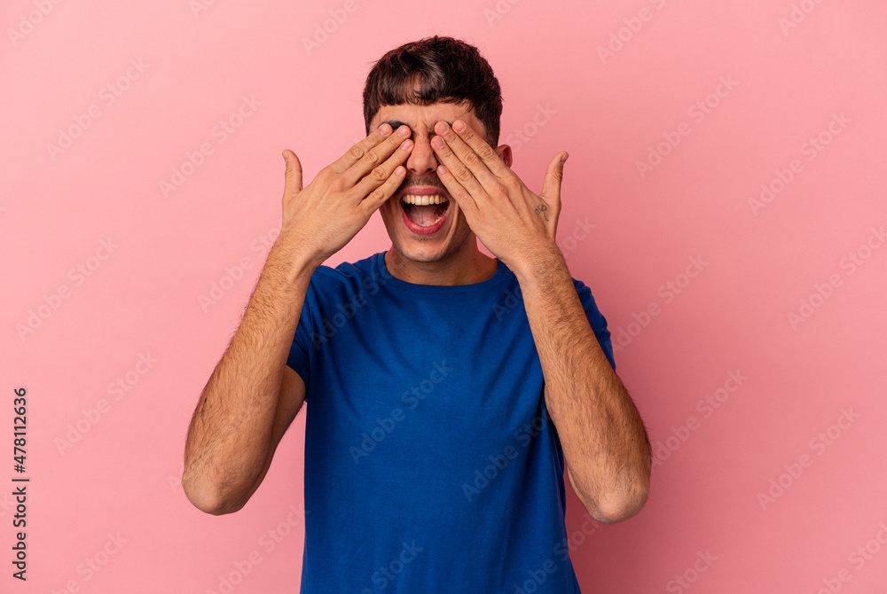 Young mixed race man isolated on pink background covers eyes with hands, smiles broadly waiting for a surprise. Young mixed race man isolated on pink background covers eyes with hands, smiles broadly waiting for a surprise.
