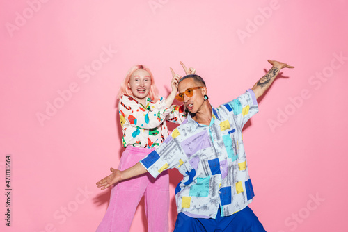 Young white couple in multicolored shirts making fun together