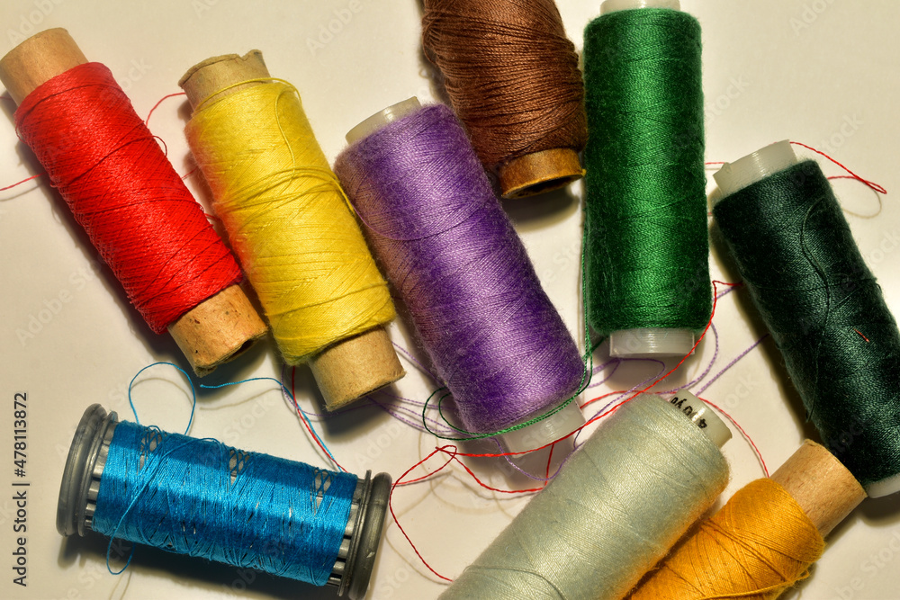 A set of sewing spools with different colors of threads on the table. A set of sewing spools with different colors of threads on the table.