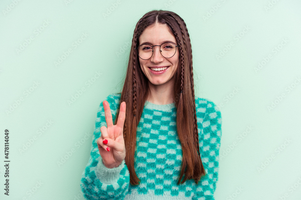 Young caucasian woman isolated on green background showing victory sign and smiling broadly. Young caucasian woman isolated on green background showing victory sign and smiling broadly.