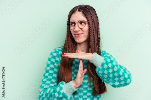 Young caucasian woman isolated on green background showing a timeout gesture.