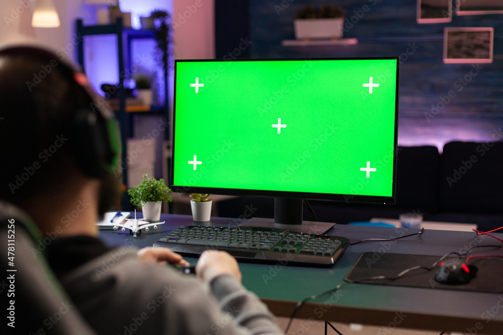 Gamer using horizontal green screen on computer. Man playing video