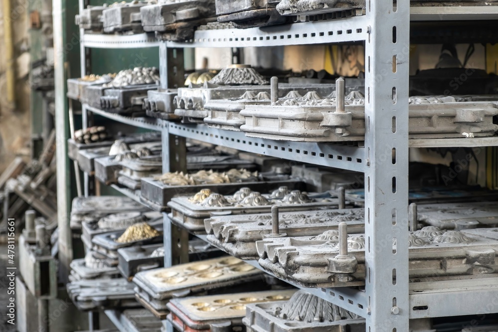 Metal molds for the production of various shapes of glass products lie on the shelves in the factory or glass manufacture.