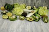 Fresh vegetables and fruits of green color lie on a wooden table