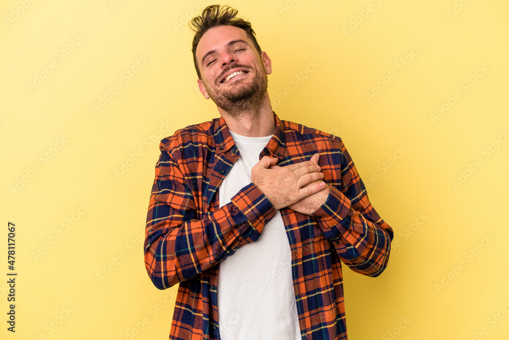 Young caucasian man isolated on yellow background has friendly expression, pressing palm to chest. Love concept. Young caucasian man isolated on yellow background has friendly expression, pressing palm to chest. Love concept.