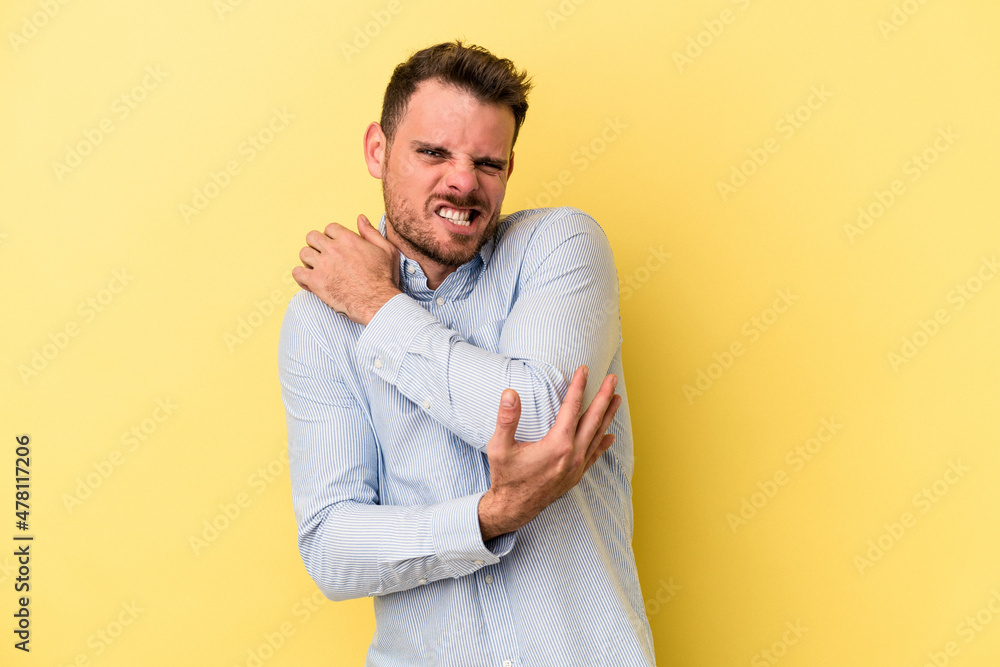 Young caucasian man isolated on yellow background massaging elbow, suffering after a bad movement. Young caucasian man isolated on yellow background massaging elbow, suffering after a bad movement.