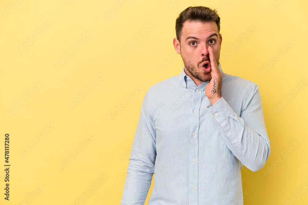 Young caucasian man isolated on yellow background is saying a secret hot braking news and looking aside Young caucasian man isolated on yellow background is saying a secret hot braking news and looking aside