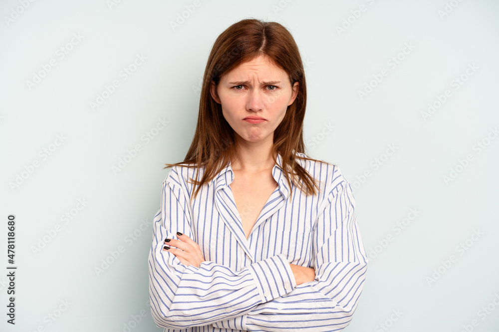 Young English woman isolated on blue background frowning face in displeasure, keeps arms folded.