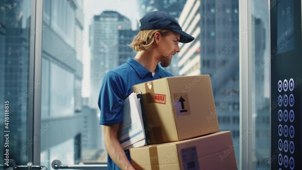 Young Delivery Person Riding Glass Elevator in Modern Office Building. Mail Courier Holding Cardboard Parcel Boxes. Handsome Mailman Delivering Fragile Packages in Business Center Lift. Young Delivery Person Riding Glass Elevator in Modern Office Building. Mail Courier Holding Cardboard Parcel Boxes. Handsome Mailman Delivering Fragile Packages in Business Center Lift.