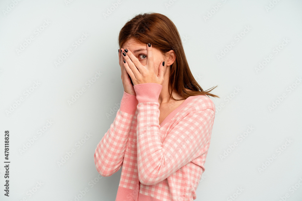 Young English woman isolated on blue background blink through fingers frightened and nervous. Young English woman isolated on blue background blink through fingers frightened and nervous.