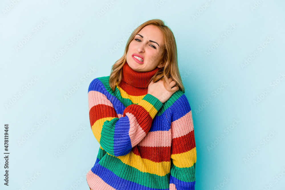 Young caucasian woman isolated on blue background having a shoulder pain. Young caucasian woman isolated on blue background having a shoulder pain.
