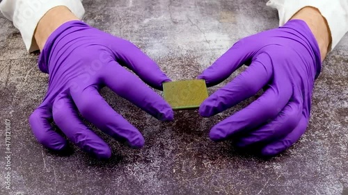 Microchip crisis with global component shortage, gloved hands showing a microprocessor.