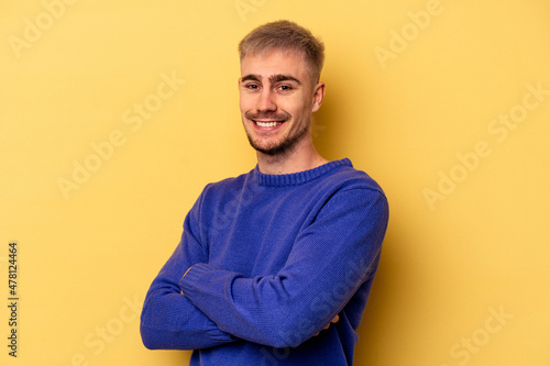 Young caucasian man isolated on yellow background happy, smiling and cheerful. © Asier