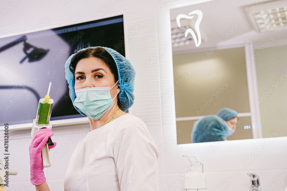 Close up photo of a dentist woman in medical uniform holding in her hand dental filling gun in her medical clinic.