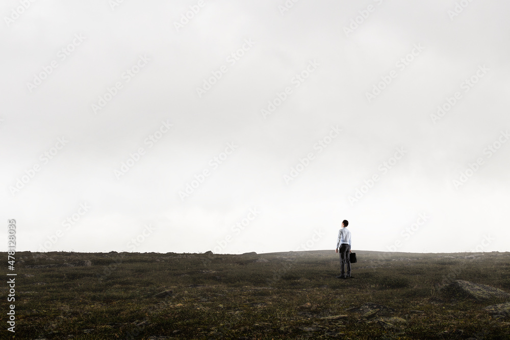 Back view of young businessman while standing with mist background Back view of young businessman while standing with mist background