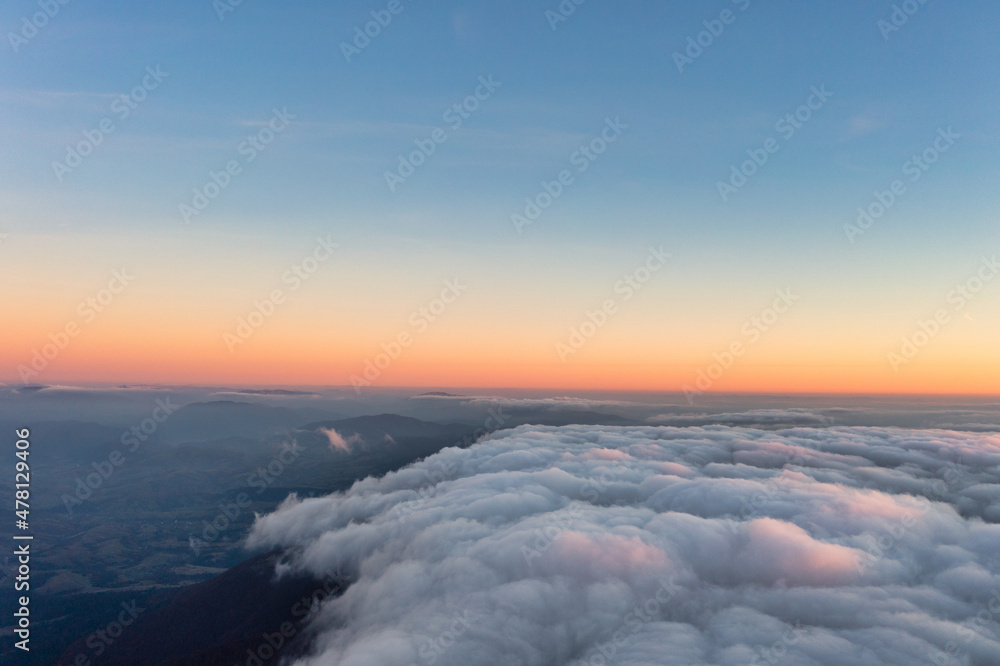 Thick fog covering mountain hills at bright pink sunset