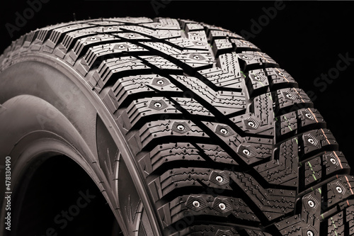 winter studded tire side view close-up on a black background © Vladimir Razgulyaev
