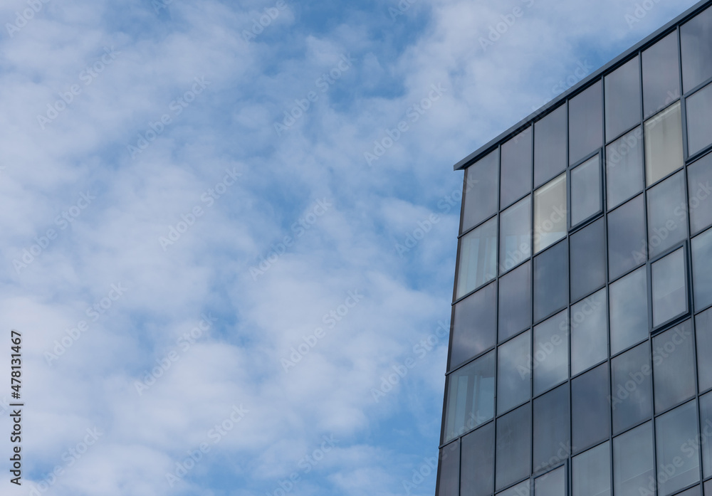 Element of a business center building made of glass on a background of blue clear sky.