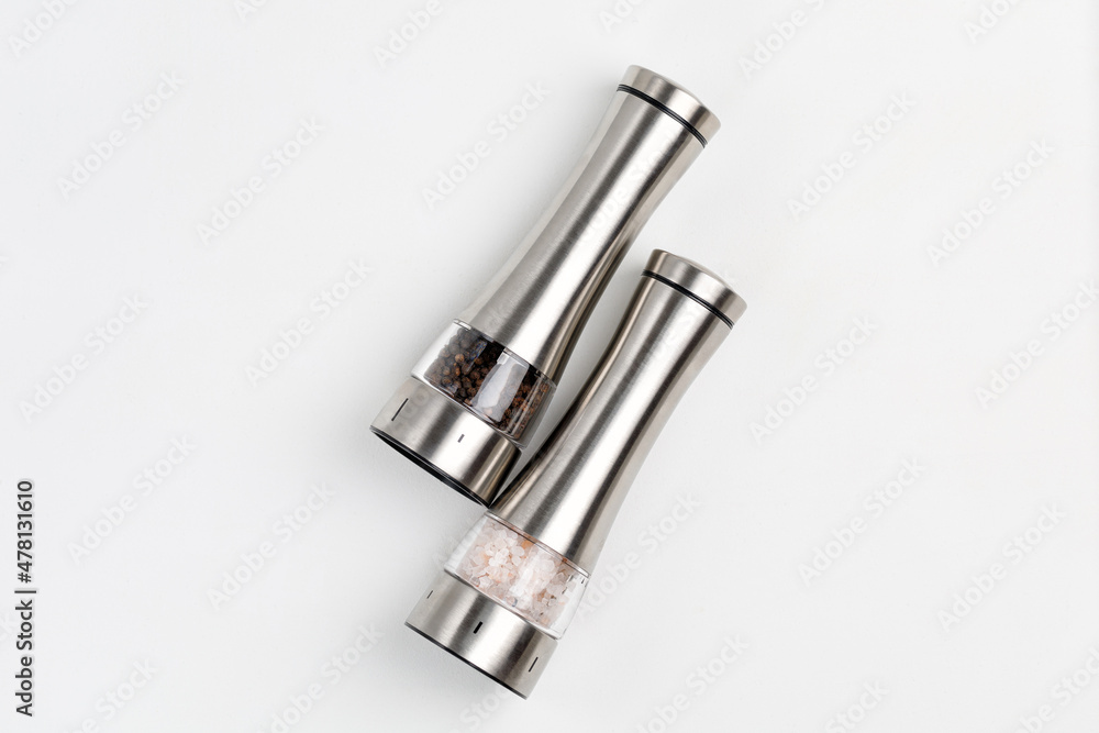Two electric spice mills for salt and pepper. Metal. On a white table Two electric spice mills for salt and pepper. Metal. On a white table