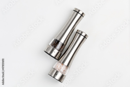 Two electric spice mills for salt and pepper. Metal. On a white table