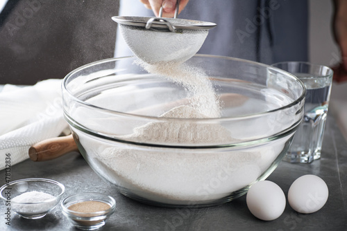 Sifting flour to make dough. Preparing flour to baking bread in kitchen at home. photo