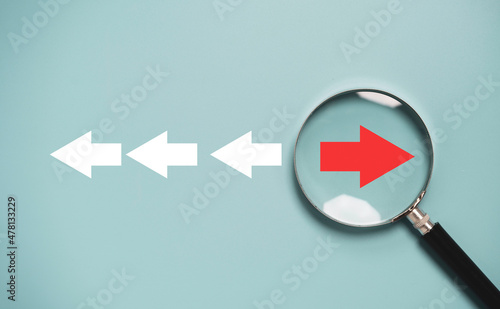 Red arrow inside of magnifier glass and different direction from white arrow for focus business disruption and technology transformation concept.