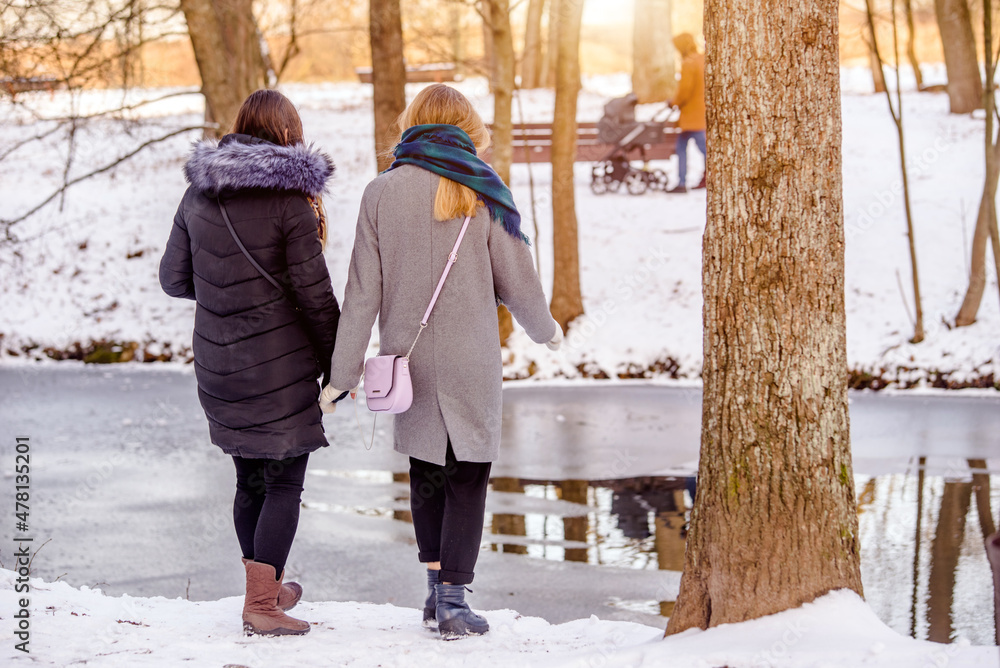 Two girls walk along the path in the winter Park
