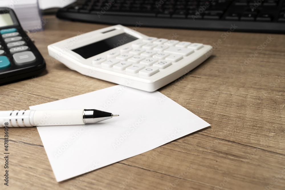 Pen on a white sheet against the background of a calculator and keyboard. Business concept. Work from home. Pen on a white sheet against the background of a calculator and keyboard. Business concept. Work from home.