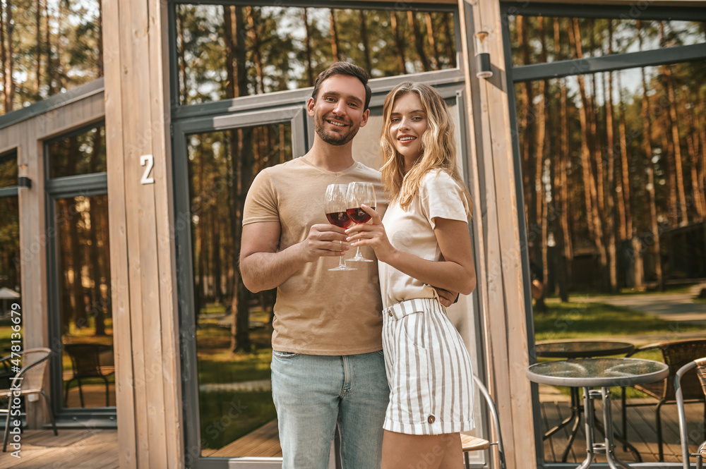 Young smiling couple holding glasses with wine and looking happy Young smiling couple holding glasses with wine and looking happy