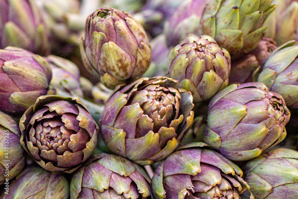 Fototapeta premium Fresh green artichokes with green leaves in a street food market, close up
