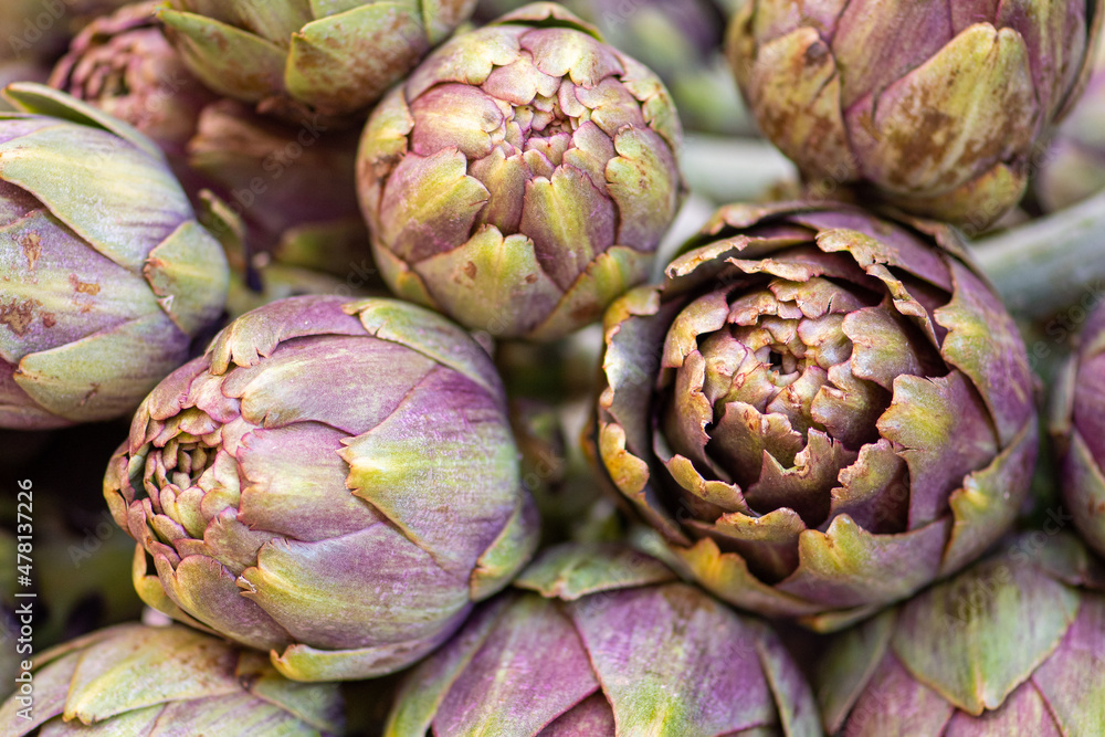 Fototapeta premium Fresh green artichokes with green leaves in a street food market, close up