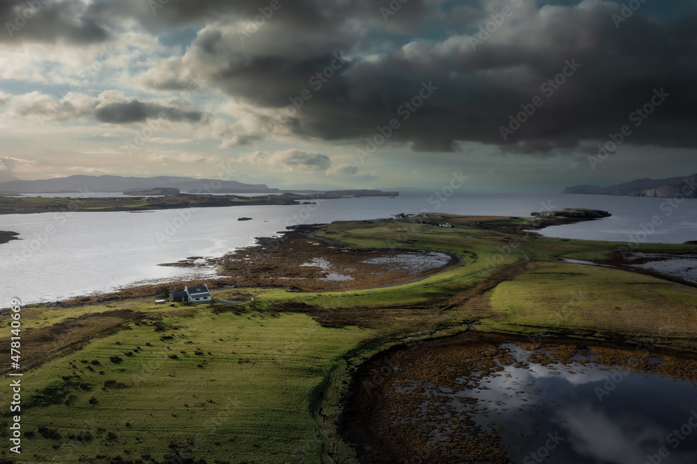 Aerial view of Isle of Skye with dramatic clouds and weather, a farm house on a small island surrounded by water Aerial view of Isle of Skye with dramatic clouds and weather, a farm house on a small island surrounded by water