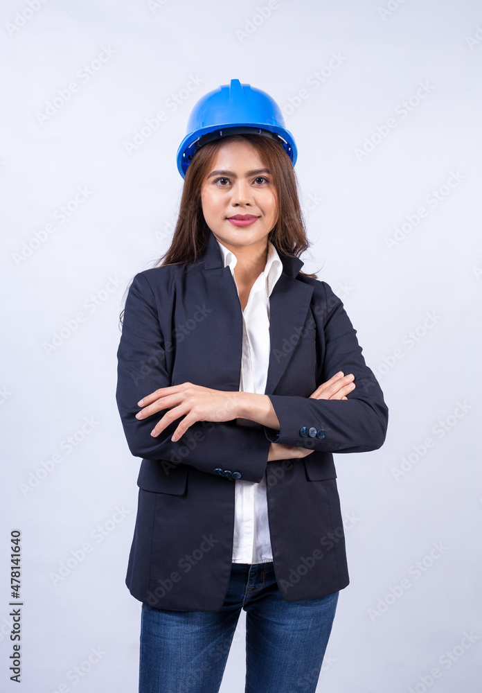 Portrait of female engineer wearing black suit and blue safety helmet with arms crossed isolated on gray background. Portrait of female engineer wearing black suit and blue safety helmet with arms crossed isolated on gray background.