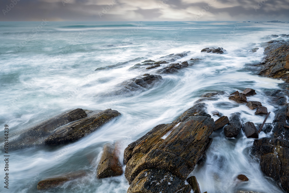 Obraz premium waves and rocks under cloudy sky in long exposure