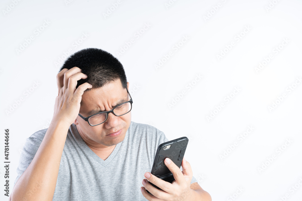 Asian man with curious and bad expression while looking at mobile phone in his hand Asian man with curious and bad expression while looking at mobile phone in his hand
