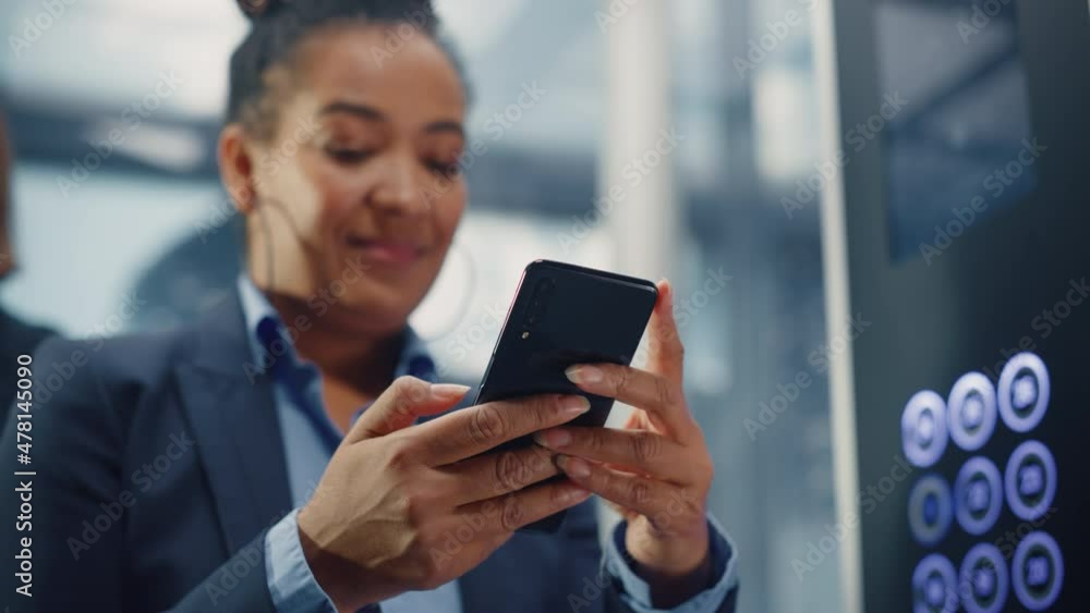 Close up of Black Adult Female Riding Crowded Glass Elevator to Office in Business Center. Successful African American Manager Using Smartphone, Write Message, Check Social Media and Emails in a Lift. Close up of Black Adult Female Riding Crowded Glass Elevator to Office in Business Center. Successful African American Manager Using Smartphone, Write Message, Check Social Media and Emails in a Lift.