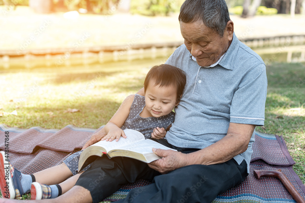 Obraz na plátně Asian elderly having faith to the Lord, God reading bible outdoor with kid