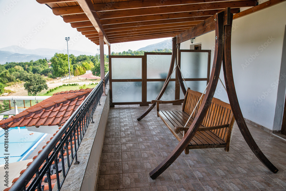 Wooden hanging bench for relaxation on the house balcony
